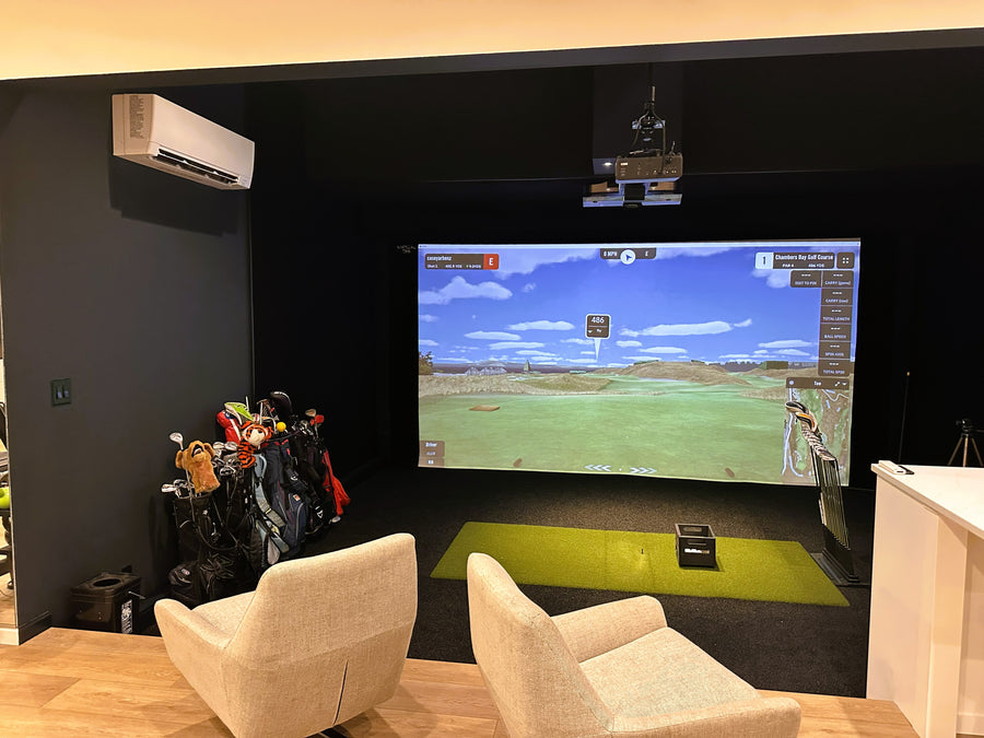 Golf simulator room inside garage with lounge area. 