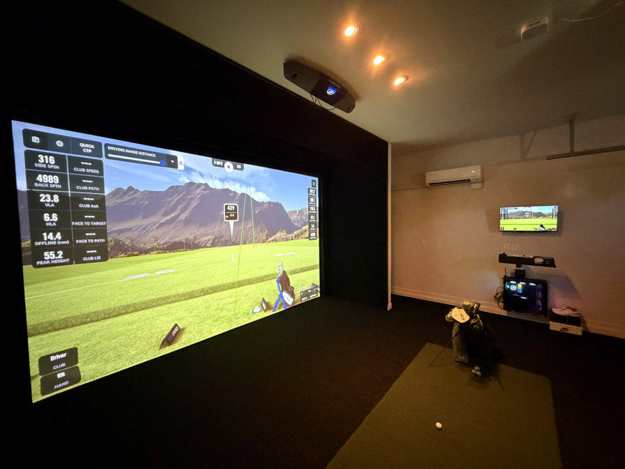 Indoor golf simulator setup with large screen displaying a golf game.