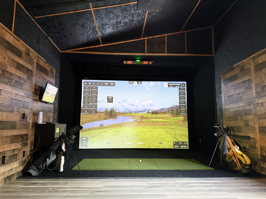 Indoor golf simulator setup with a large screen displaying a golf course.