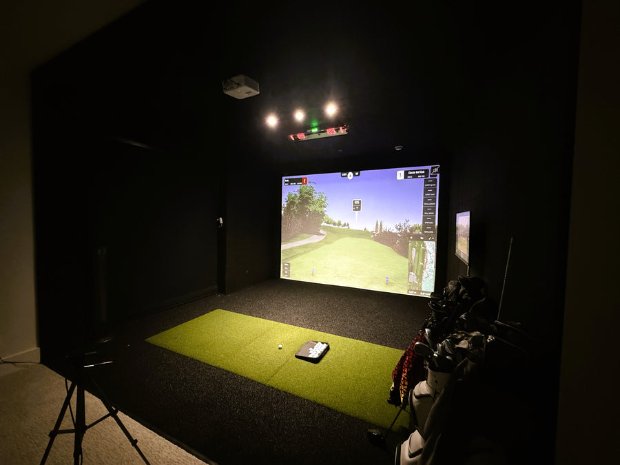 Indoor golf simulator setup with screen displaying a golf course.