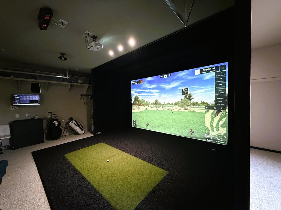 Indoor golf simulator setup with a large screen displaying a golf course.