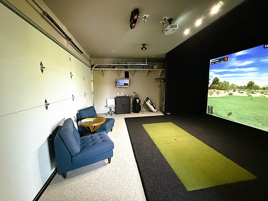 Indoor golf simulator setup in a room with a blue couch and a screen displaying a golf course.