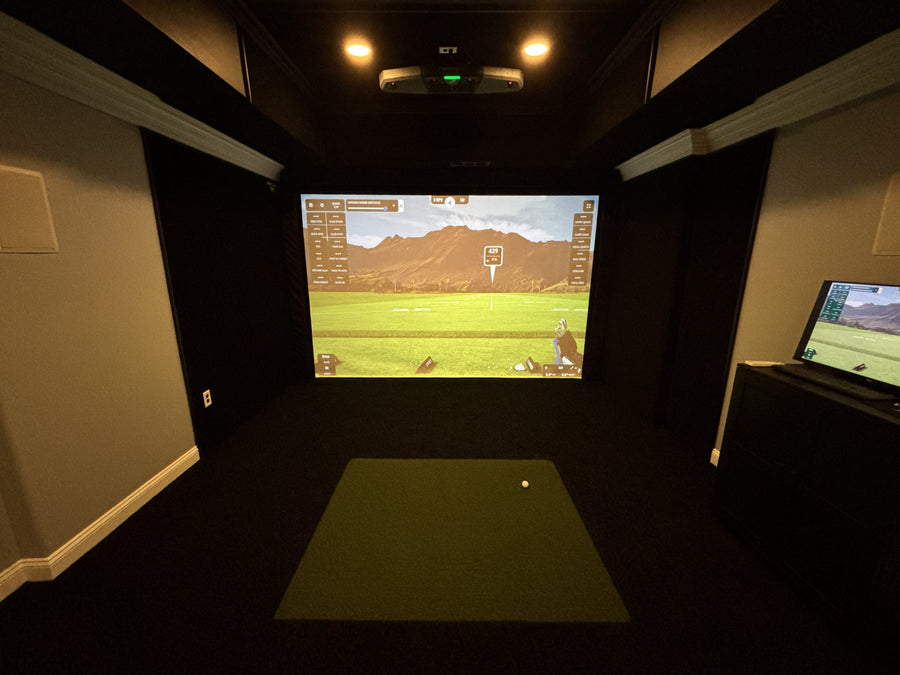 Indoor golf simulator setup with screen displaying a golf course.