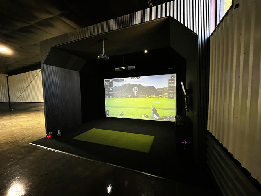 Indoor golf simulator setup with a screen displaying a golf course.