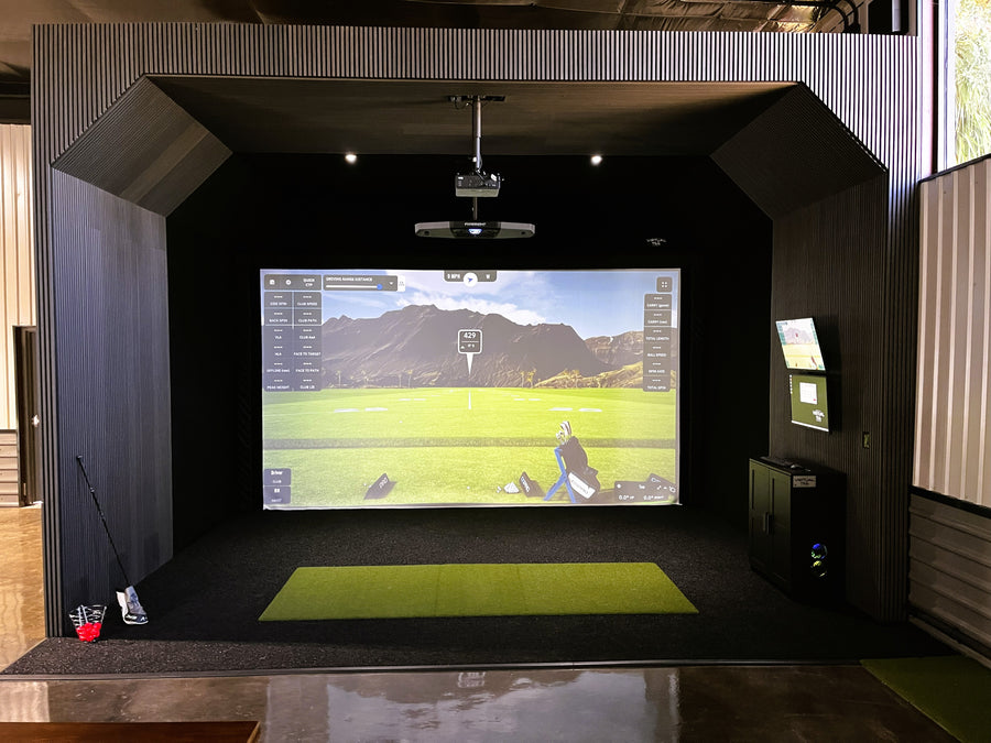 Indoor golf simulator setup with screen displaying a golf course.