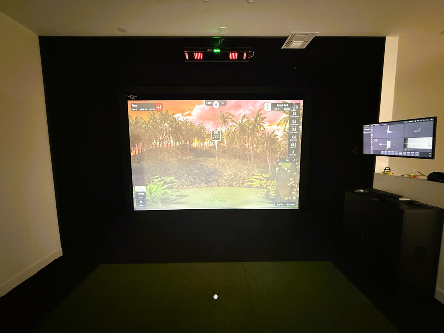 Golf simulator with outdoor scene on a large screen with control panel in a room.