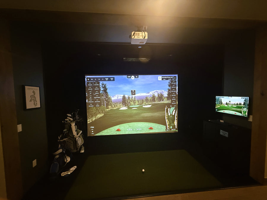 Indoor golf simulator setup with two screens displaying a golf course.