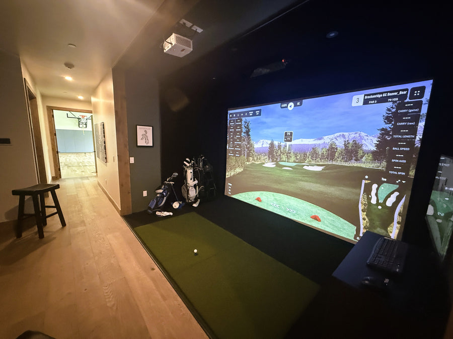 Indoor golf simulator setup with a screen displaying a golf course.