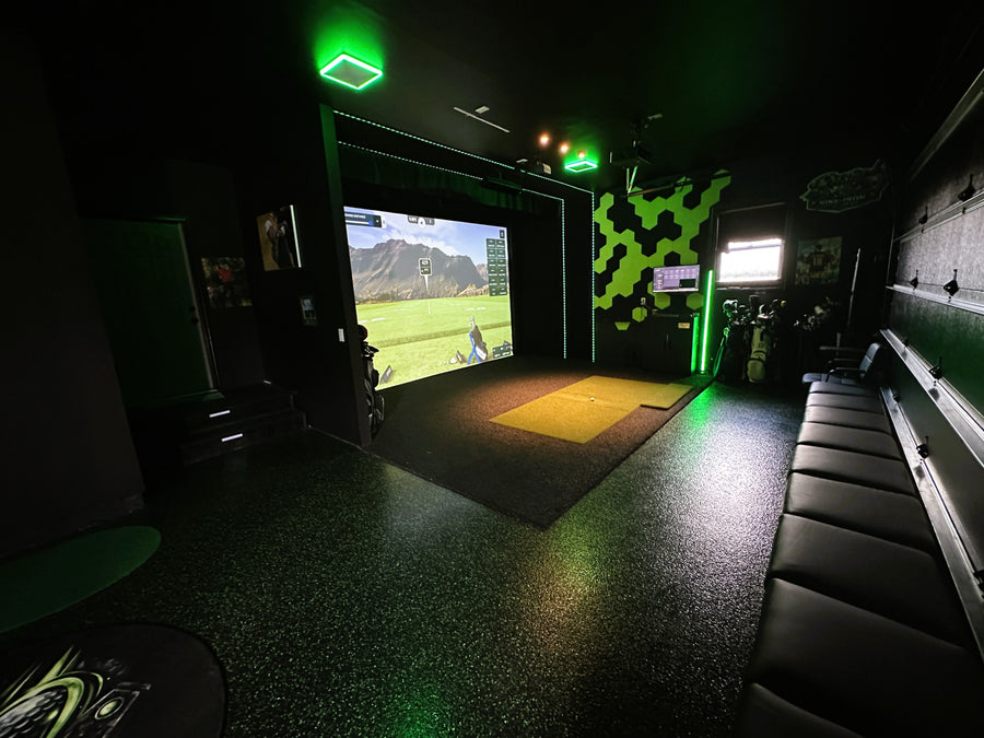 Indoor golf simulator setup with screen displaying a golf course.