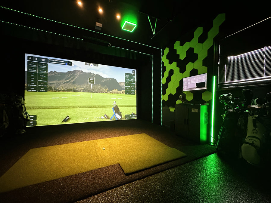 Indoor golf simulator setup with a screen displaying a golf course.