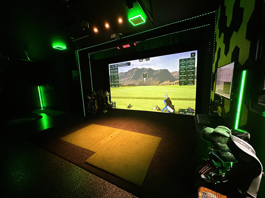 Indoor golf simulator setup with screen displaying a golf course.