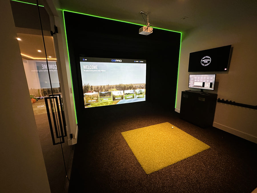 Indoor golf simulator setup with large screen and control panel.