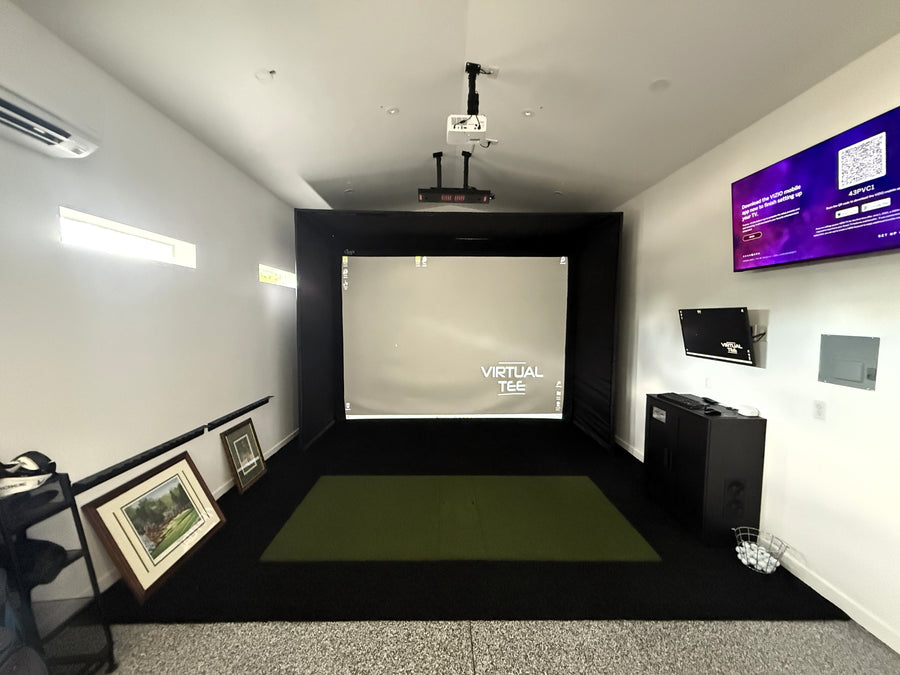 Indoor golf simulator setup with screen, projector, and equipment in a room.