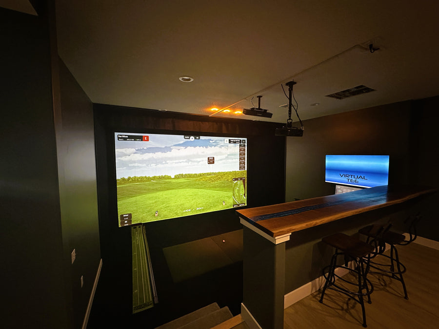 Indoor Golf Simulator setup with large screen displaying sports game and smaller screen on bar counter.