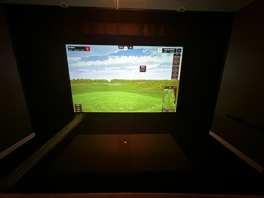 Golf simulator screen displaying a virtual golf course in a dark room.