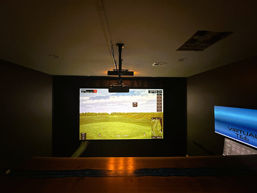 Golf simulator setup with screen displaying a golf course and 'Virtual Tee' branding.
