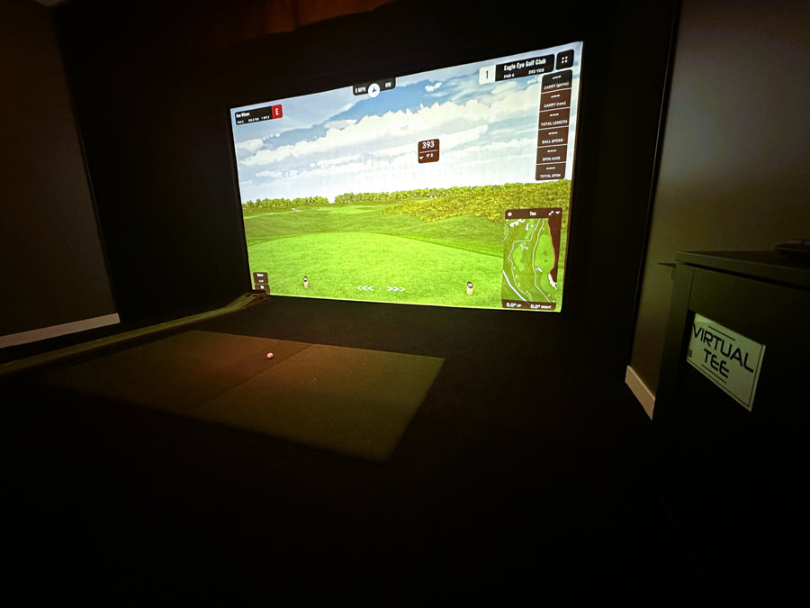 Golf simulator setup with screen displaying a golf course on a dark background