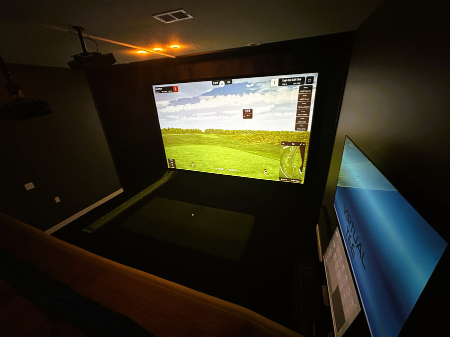 Golf simulator setup with screen displaying a golf course in a dark room.