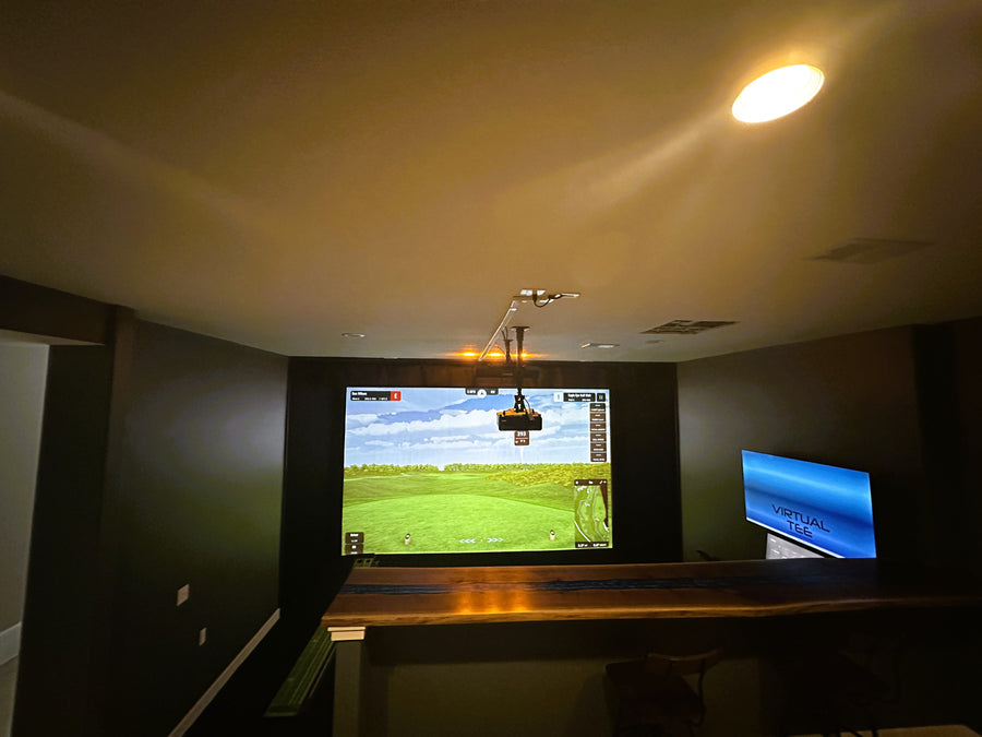 Indoor recreational area with a large screen displaying a virtual golf game.