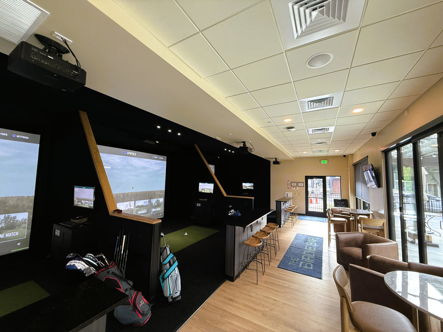 Modern indoor recreational area with multiple screens, chairs, and a casual setup.