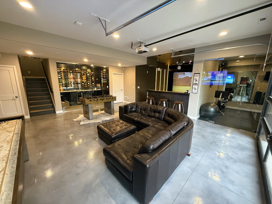 Modern living room with a large brown sectional sofa, coffee table, and a golf simulator.