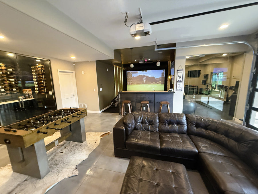 Modern living room with leather sectional, foosball table, and a golf simulator.