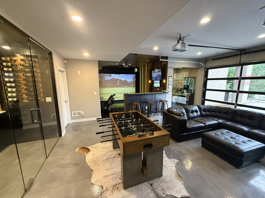 Modern living room with a foosball table, sectional sofa, and a golf simulator.
