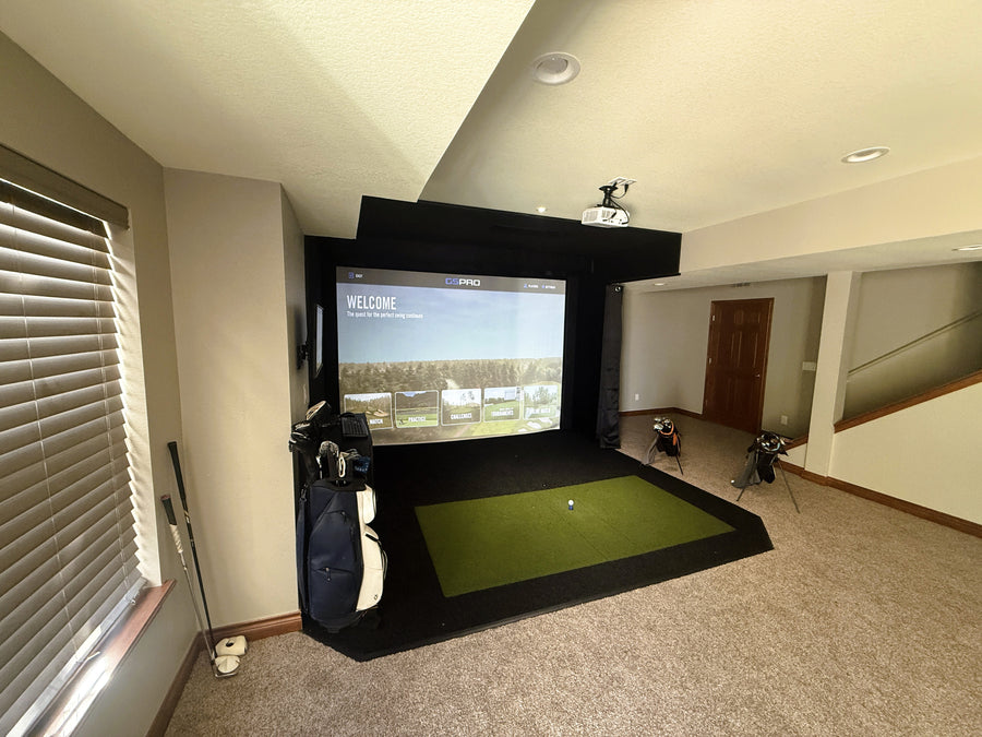 Indoor golf simulator setup in a room with a screen displaying a golf course.
