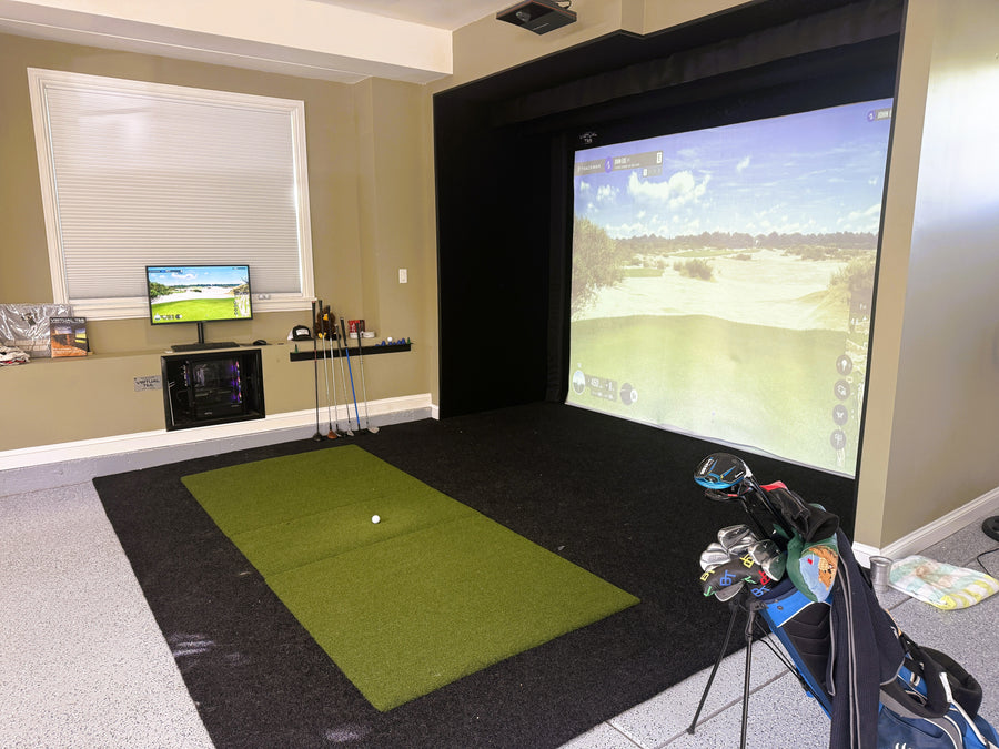 Indoor golf simulator setup with projection screen and golf equipment.