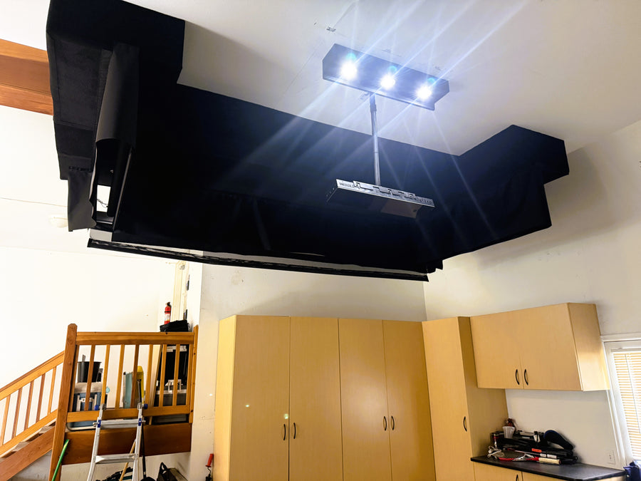 Retractable golf simulator setup with wooden cabinets and a staircase.