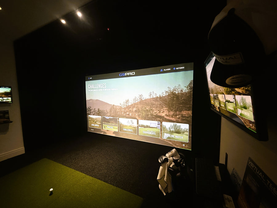Golf simulator setup with screen displaying a golf course on the wall.