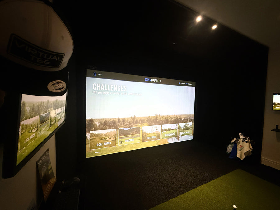 Golf simulator setup with a screen displaying a golf course and a golf club on a stand.