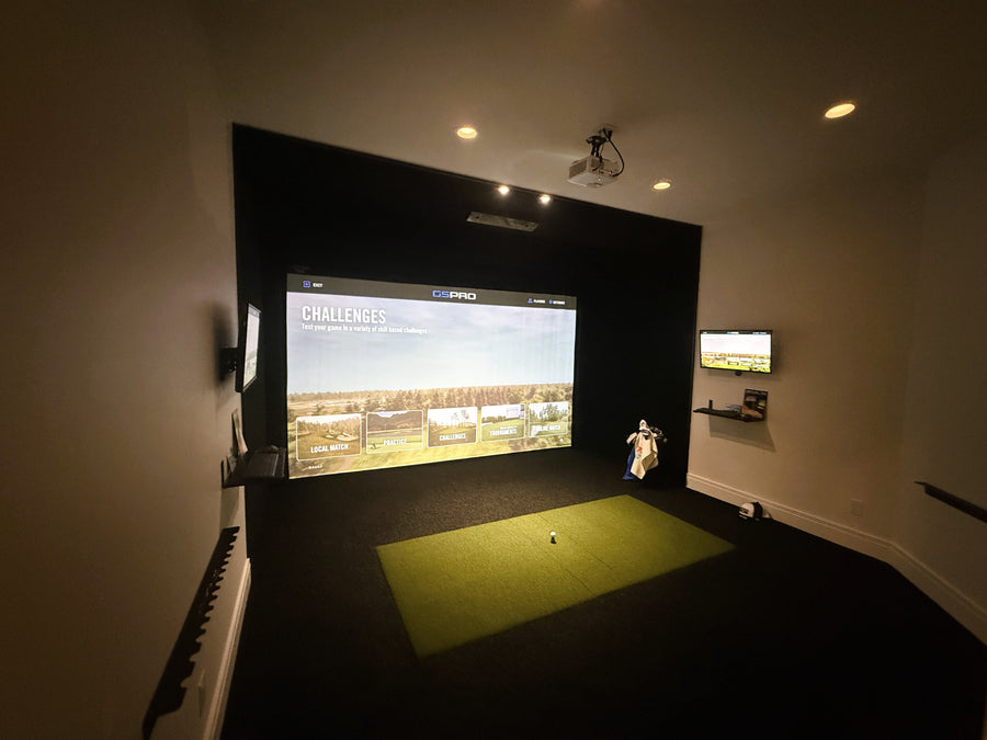 Indoor golf simulator setup in a room with a large screen displaying a golf course.