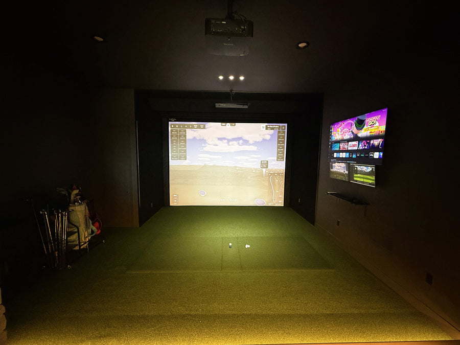 Indoor golf simulator setup with screen and projection in a dark room