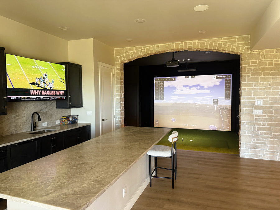 Modern indoor golf simulator room with large screens displaying sports content.