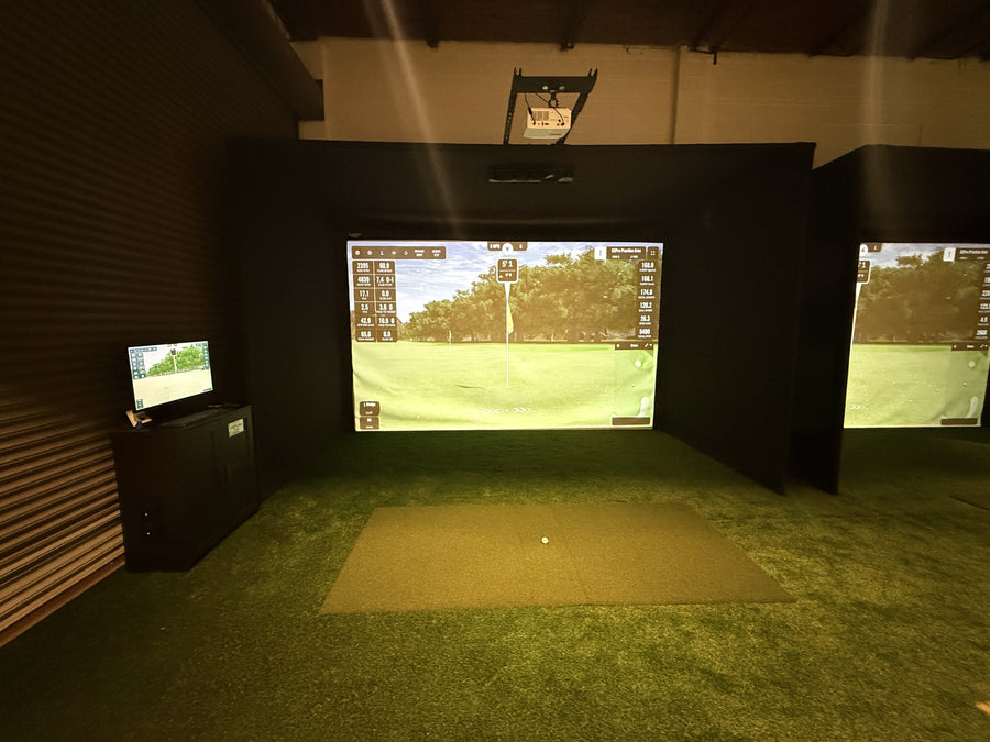 Indoor golf simulator setup with two screens displaying a golf course.
