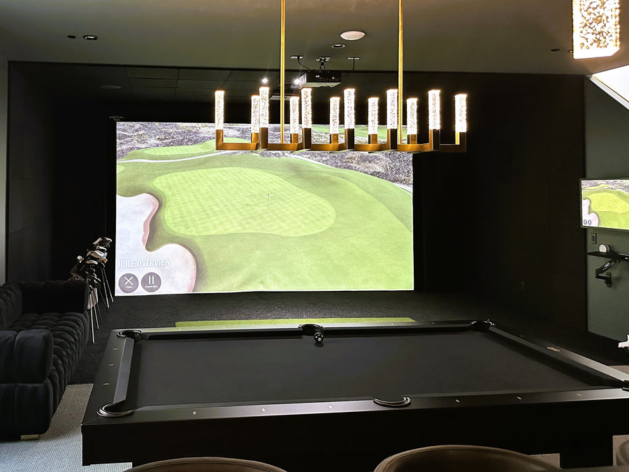 Golf simulator setup in a room with a pool table and chairs.