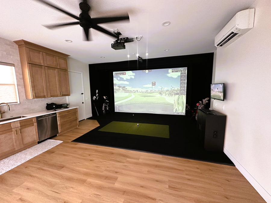 Indoor golf simulator setup in a home with a screen displaying a golf course.