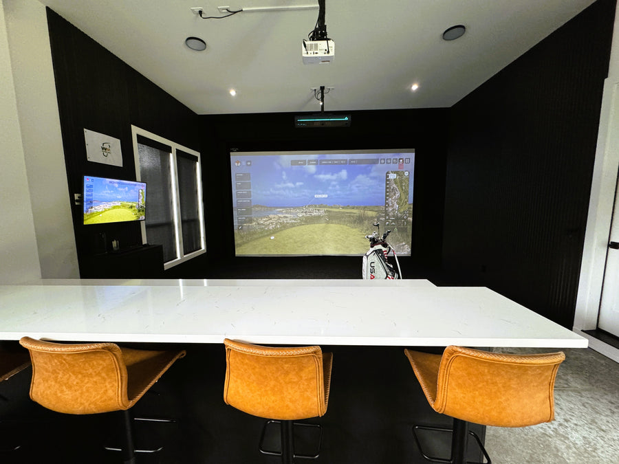 Modern room with a large white table and orange chairs, featuring a screen displaying a virtual landscape.