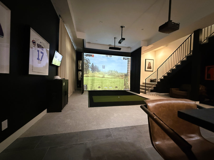 Indoor golf simulator setup in a modern living room with a large screen and gaming equipment.