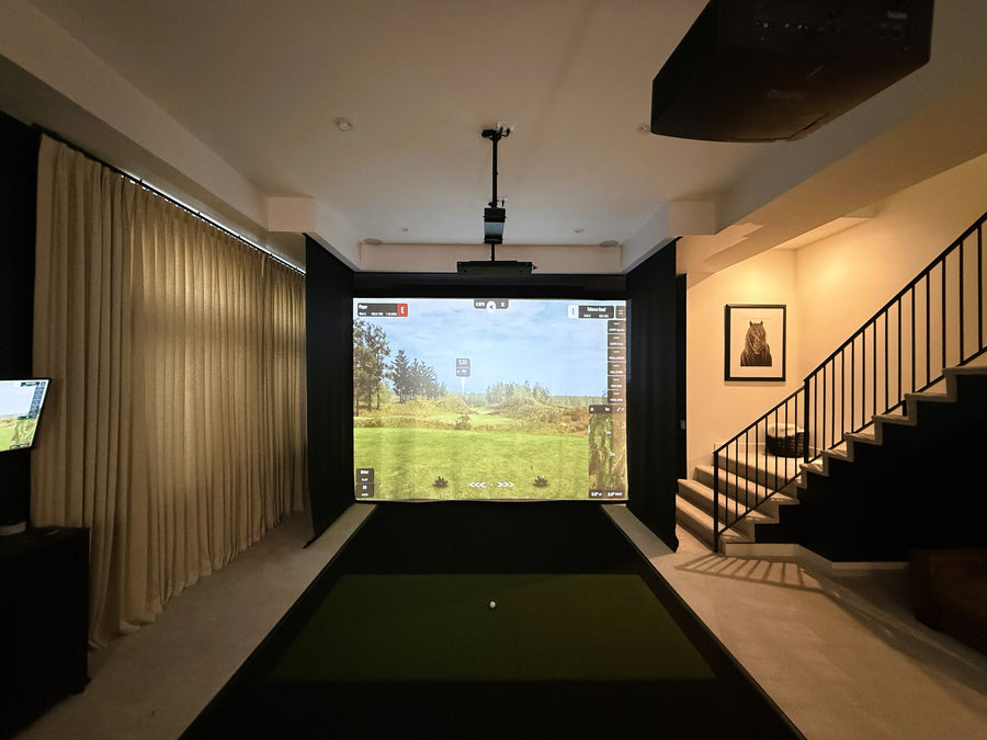 Indoor golf simulator setup in a home entertainment room with a screen displaying a golf course.