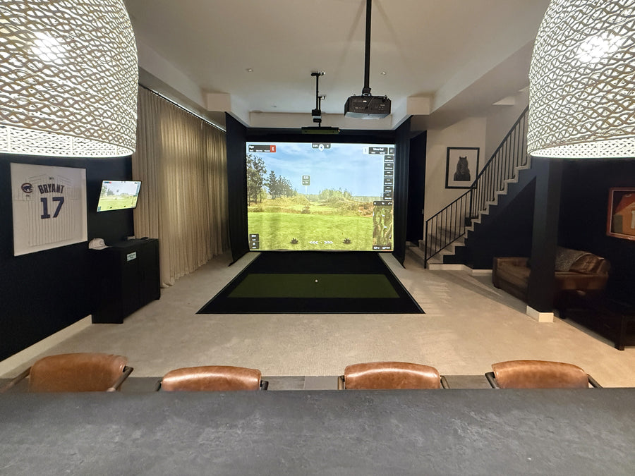 Indoor golf simulator setup in a modern living room with a TV screen displaying a golf course.