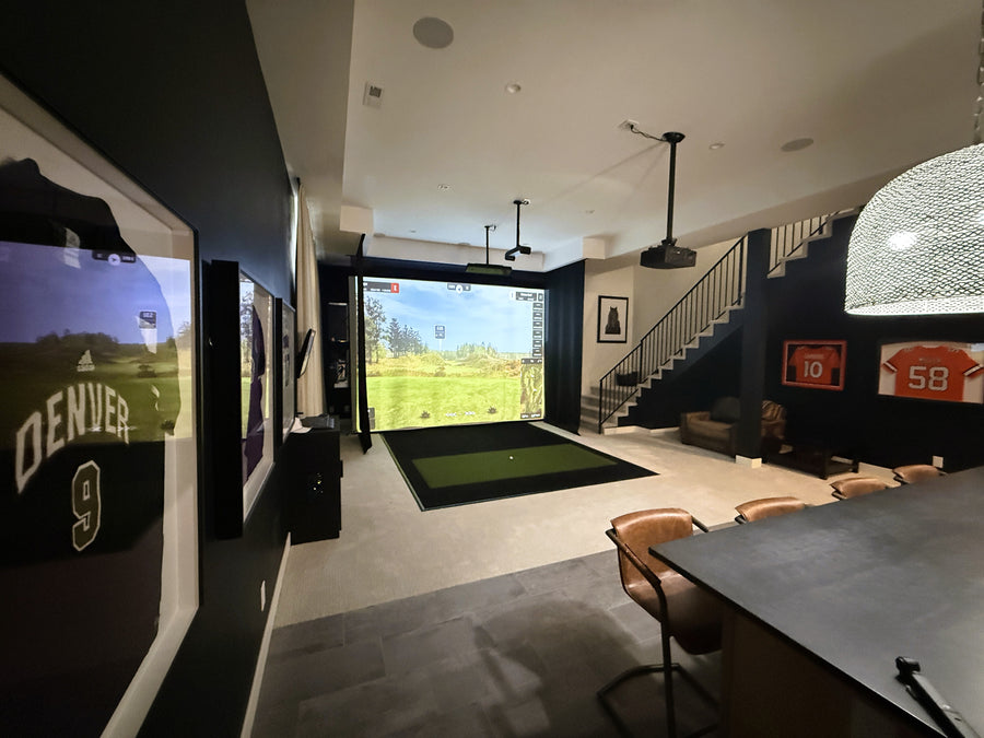 Modern indoor golf simulator setup in a living room with sports memorabilia.