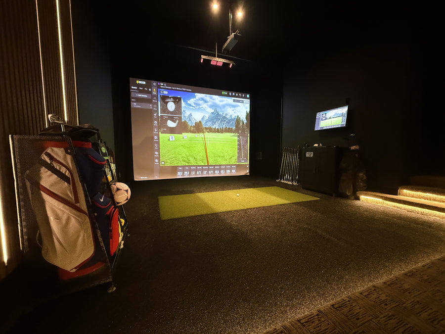 Indoor golf simulator setup with screen displaying a golf course.