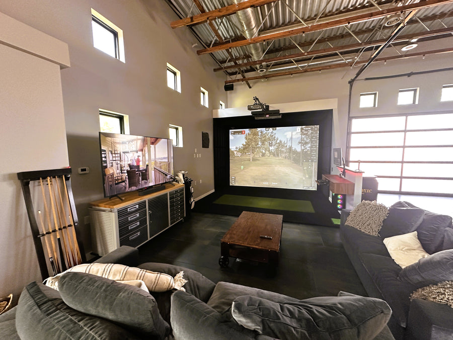 Golf simulator setup with large screens, comfortable seating, and decorative elements.