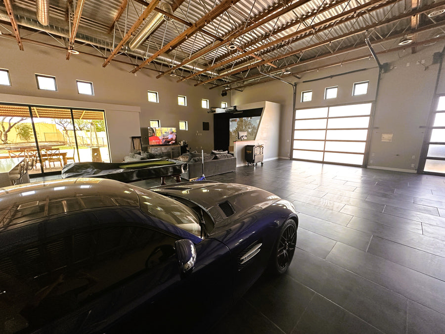 Modern garage with a car, living area, golf simulator and large windows.