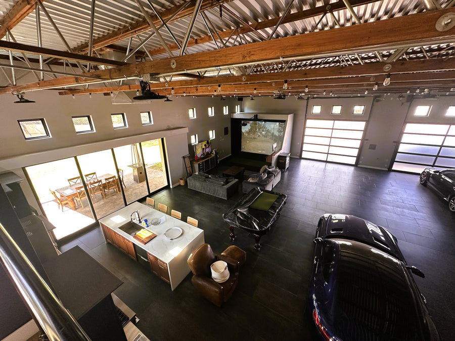 Modern open-concept living space with kitchen, dining area, golf simulator and garage.