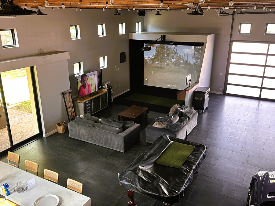 Golf simulator with a large screen TV and gaming setup.
