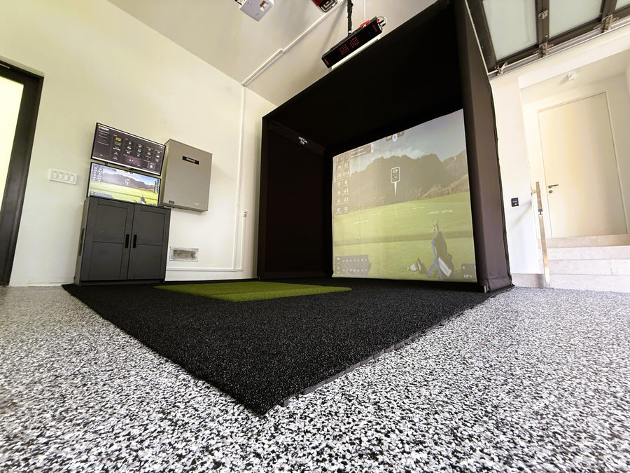 Indoor golf simulator setup with screen displaying a golf course.