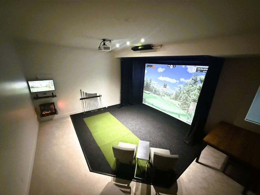 Indoor golf simulator setup in a room with a screen displaying a golf course.